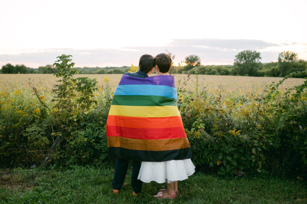 Couple with LGBTQ+ flag at their Heritage Prairie Farm wedding